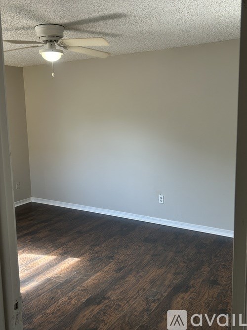 A room with a ceiling fan and wood flooring.