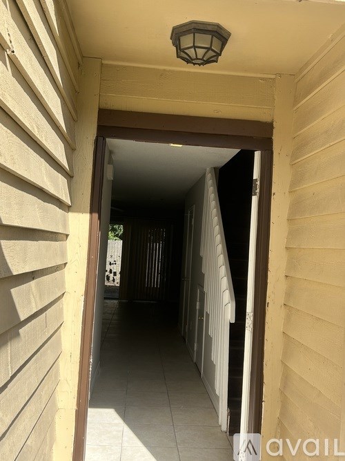 A hallway with a light on the ceiling and a door at the end.