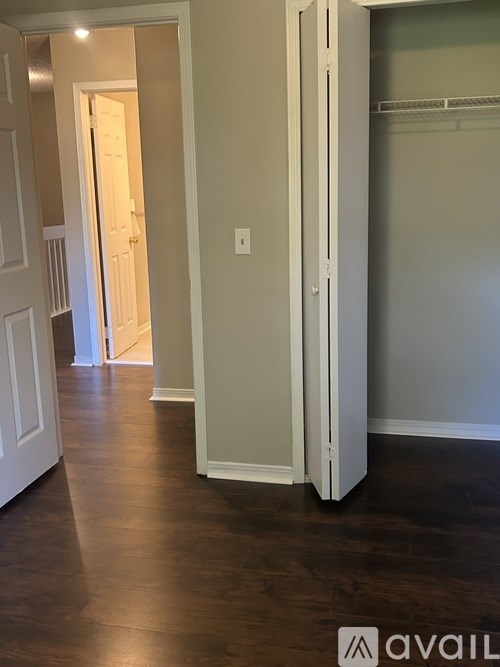 A white door is open to a room with wood floors.