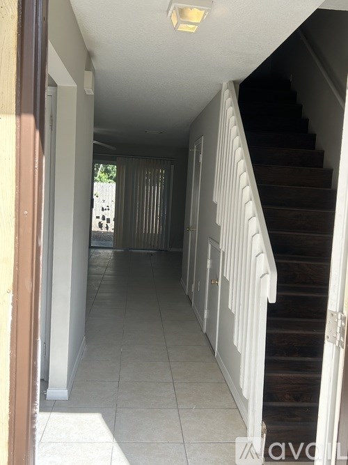 A hallway with a staircase on the right and a door on the left.
