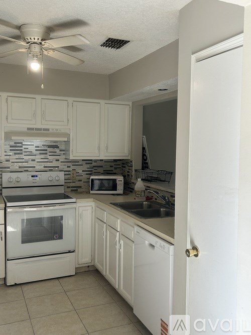A kitchen with white appliances and cabinets.