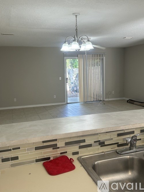 A kitchen with a sink, a red bag on the counter, and a window with blinds.