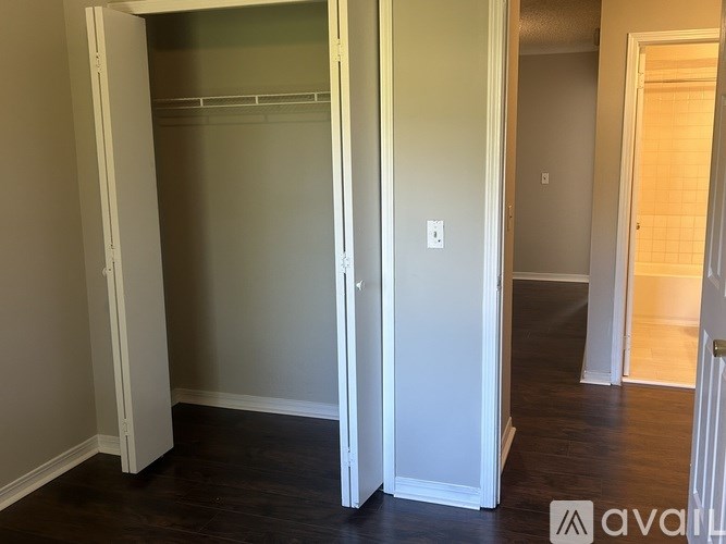 A white closet with a door open and a white wall with a switch.