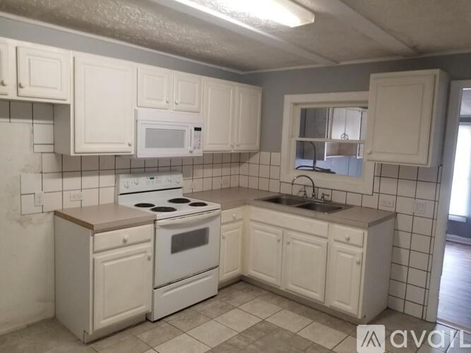 A kitchen with white appliances and cabinets.