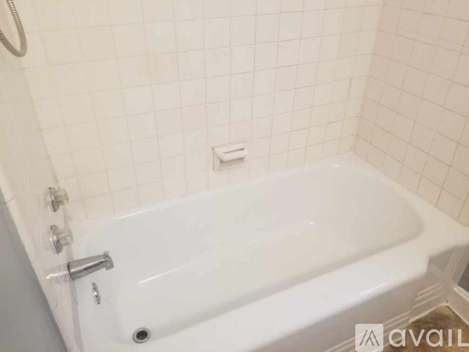 A white bathtub with a shower head and faucet.