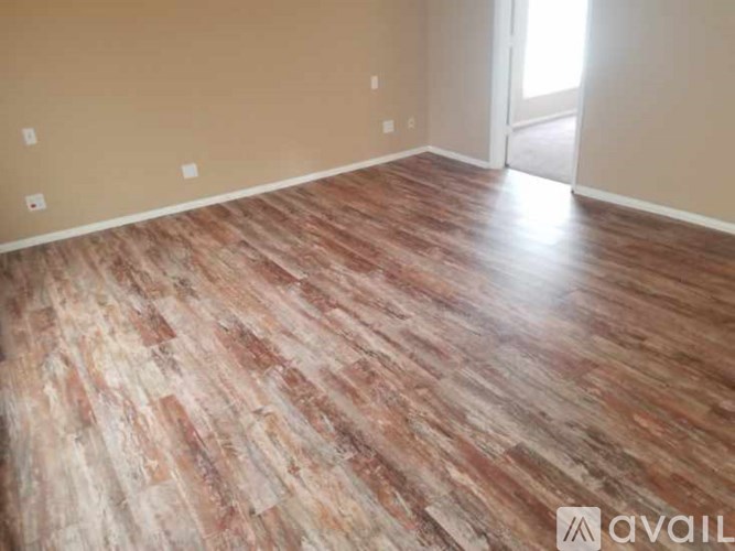 A room with wooden flooring and a doorway leading to another room.