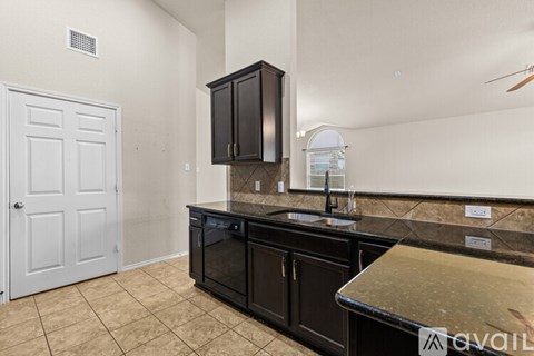 A kitchen with black cabinets and a white door.