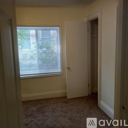 A room with a carpeted floor and a window with blinds.
