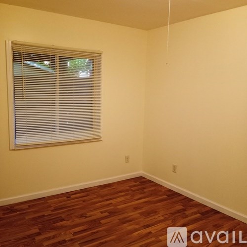 A room with wooden flooring and a window with blinds.