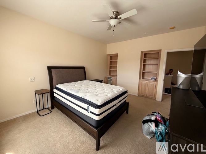 A bedroom with a large bed and a ceiling fan.