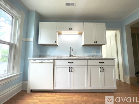 A kitchen with white cabinets and a blue wall.
