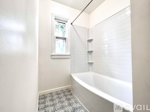 A white bathroom with a tub and a window.