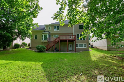 A house with a green lawn and trees in the foreground.