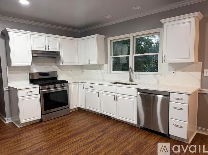 A spacious room with wood flooring and a ceiling fan.