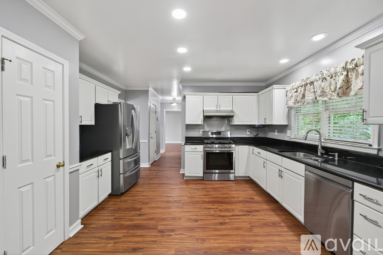 A spacious kitchen with white cabinets and wooden floors.