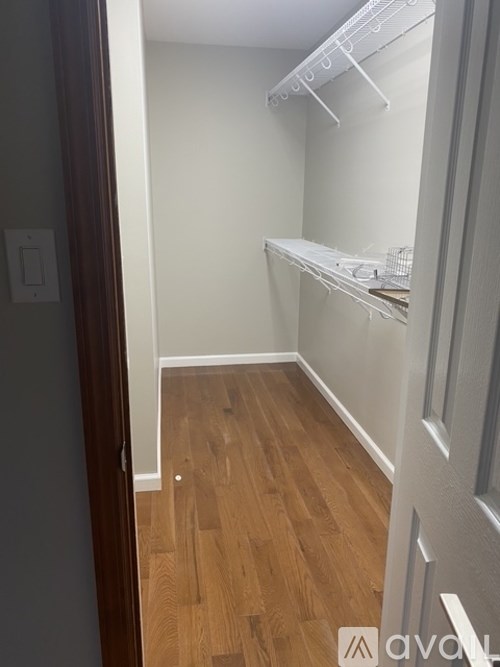 A white closet with shelves and a wooden floor.