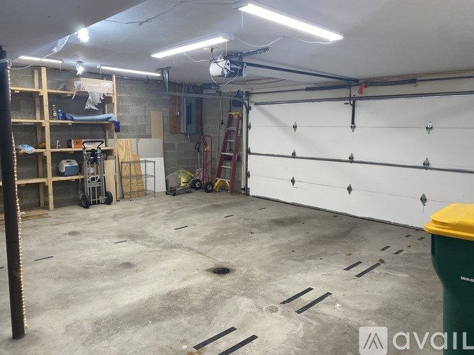 A large garage with a white wall and a yellow trash can.
