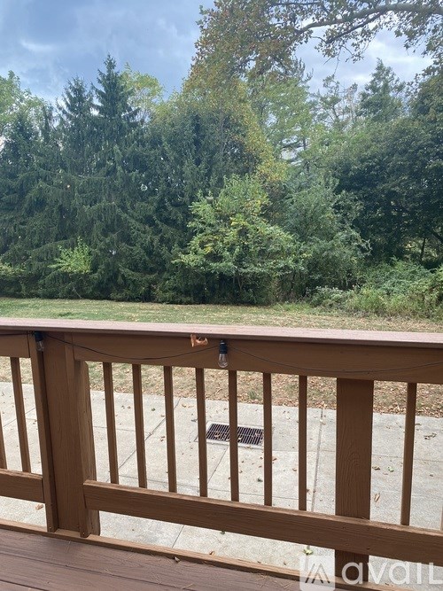 A wooden deck with a railing and a view of a green forest.