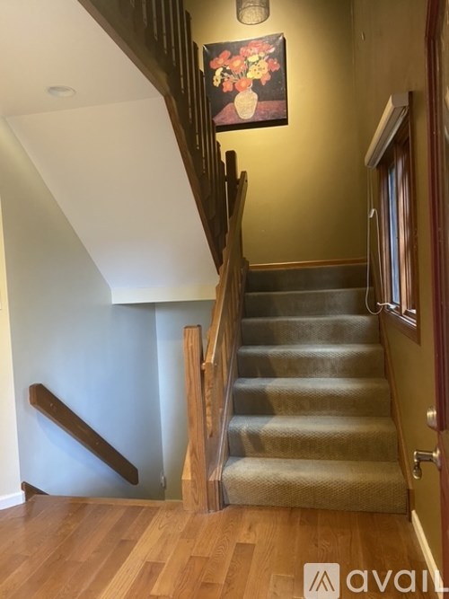 A staircase with a wooden handrail and a painting on the wall.