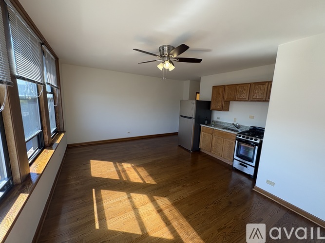 A spacious kitchen with wooden floors and a ceiling fan.