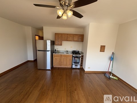 A kitchen with wooden floors and a ceiling fan.