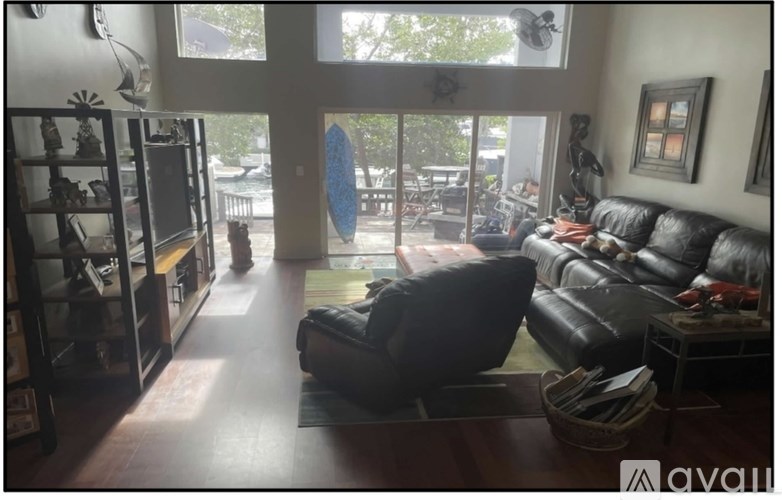 A living room with a black couch and a blue surfboard in the background.