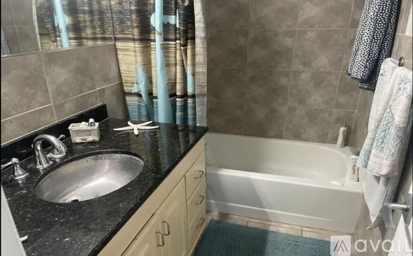 A bathroom with a black granite countertop and a white bathtub.