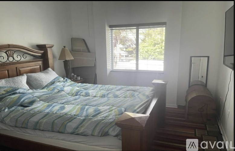 A bedroom with a bed, nightstand, and window.