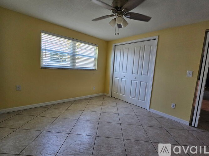 A room with yellow walls, a ceiling fan, and a door.