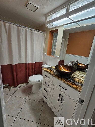 A bathroom with a toilet, sink, and shower curtain.