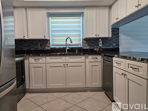 A kitchen with white cabinets and black countertops.