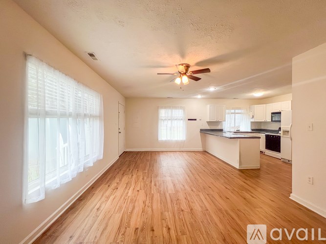 A spacious living room with wooden floors and a ceiling fan.