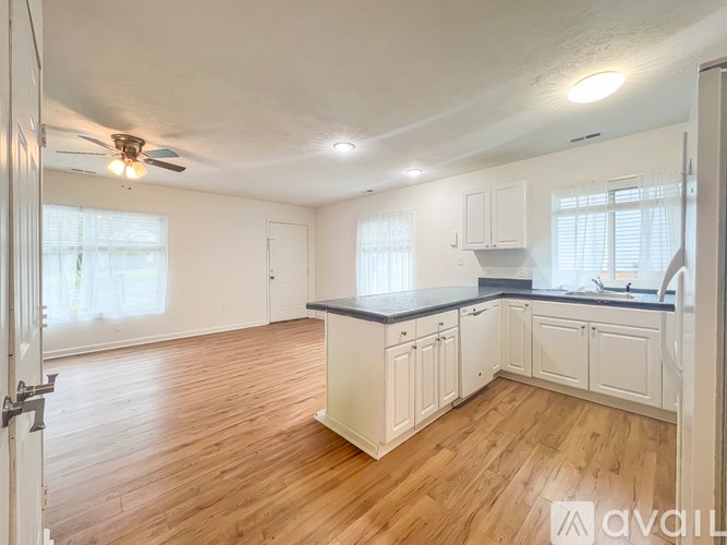 A kitchen with white cabinets and a wooden floor.