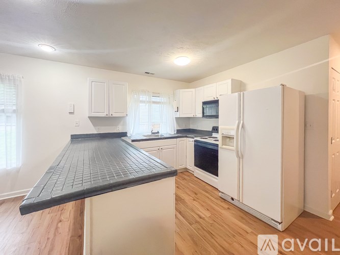 A kitchen with white cabinets and a black countertop.
