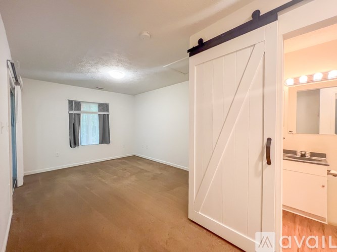 A room with a white door and a window with curtains.
