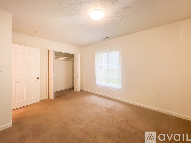 A room with a carpeted floor, a door, and a window.
