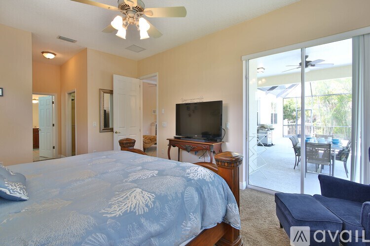 A bedroom with a bed, a television, and a sliding glass door.