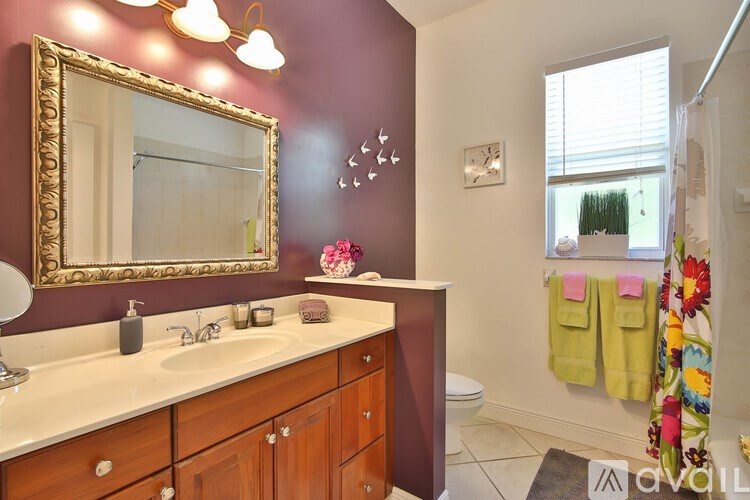 A bathroom with a maroon wall and a gold framed mirror.