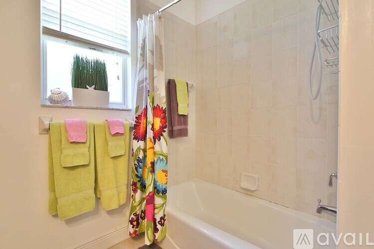 A bathroom with a white tub, a window, and a shower curtain.