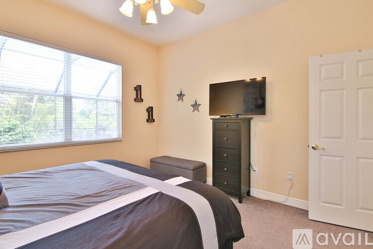 A bedroom with a large bed, a dresser, and a flat-screen TV mounted on the wall.