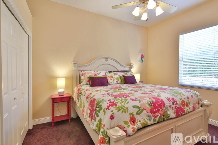 A bedroom with a floral bedspread and a red side table.