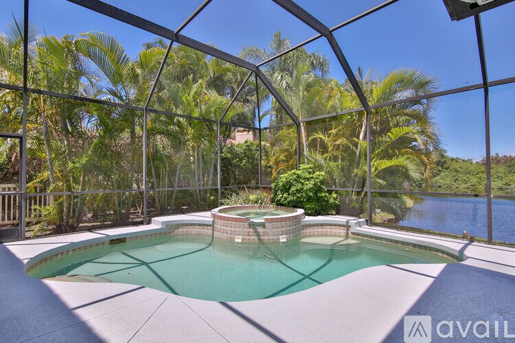 A pool surrounded by a glass wall with trees in the background.