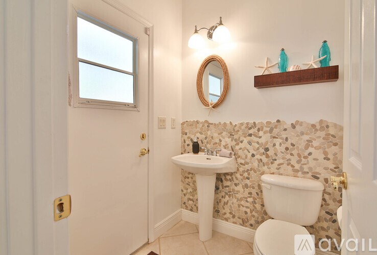 A bathroom with a sink, toilet, and a window.