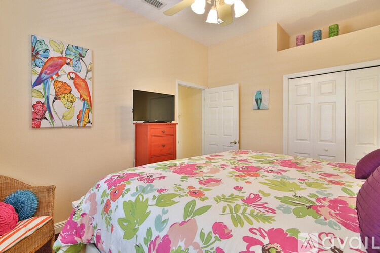 A bedroom with a floral bedspread and a painting on the wall.