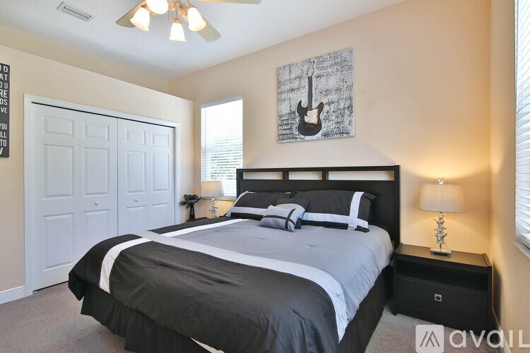 A bedroom with a large bed and a guitar picture on the wall.
