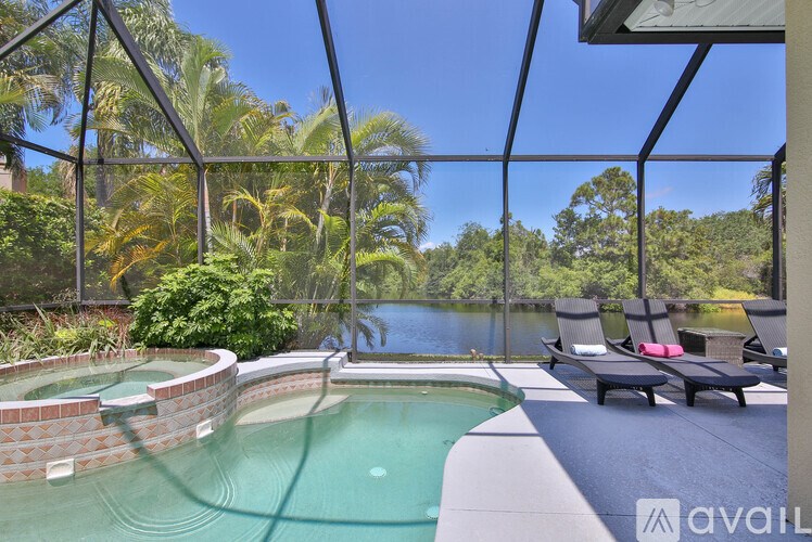 A hot tub sits in the middle of a patio with a view of a lake and trees.