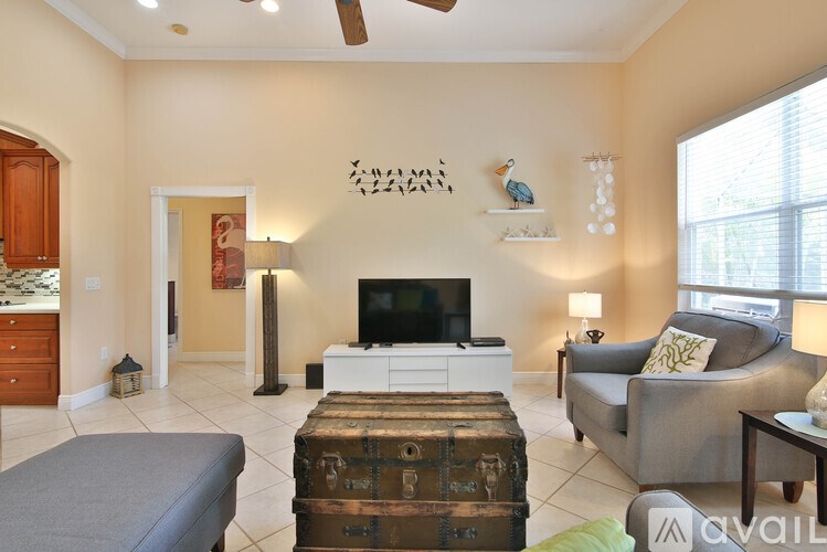 A living room with a grey ottoman and a grey couch.