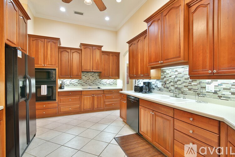 A kitchen with wooden cabinets and a black refrigerator.