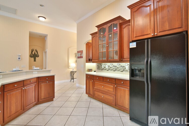 A kitchen with wooden cabinets and a black refrigerator.