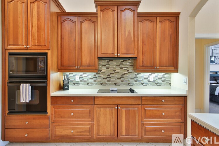 A kitchen with wooden cabinets and a stone backsplash.